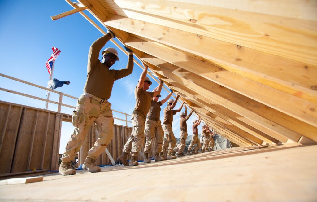 Men working together in construction raising a wood outside wall.
